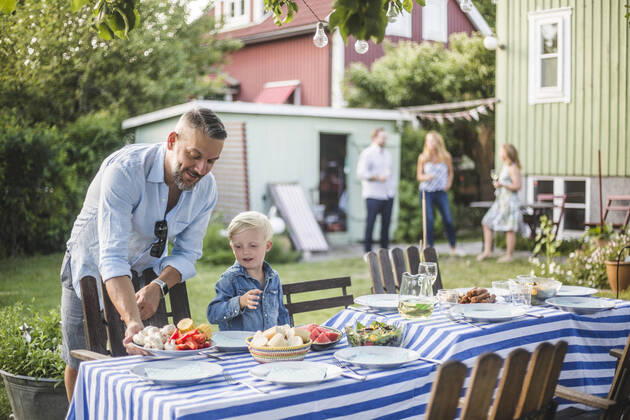 IMAGO Creative: Landleben - Essen Father talking to son while arranging food plate on table in backyard , model released, property released Copyright: xMaskotx , MA74074