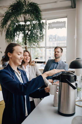 Smiling colleagues looking at businesswoman having coffee during break , model released, property released Copyright: xMaskotx , MA75746