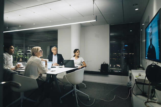 Colleagues looking at businessman during video conference meeting at night in office Sweden, Stockholm, model released, property released Copyright: xMaskotx , MA79677