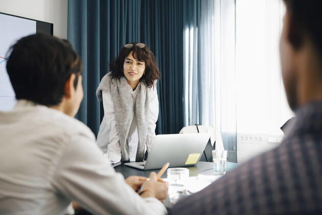 Smiling businesswoman planning strategy with male colleagues in board room during meeting Sweden, Stockholm, model released, property released Copyright: xMaskotx , MA80172