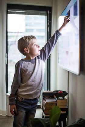 Boy touching digital display of smart television set at modern home Sweden, Stockholm, model released, property released Copyright: xMaskotx , MA80374
