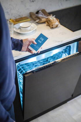 Cropped image of man using mobile app while standing by dishwasher at smart home Sweden, Stockholm, model released, property released Copyright: xMaskotx , MA80398