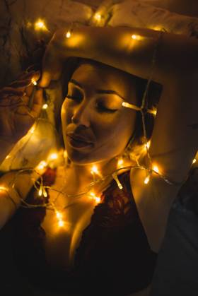 From above young beautiful woman in underwear lying in bed surrounded by light garland, Model released Copyright: xMURxStudiosx MR