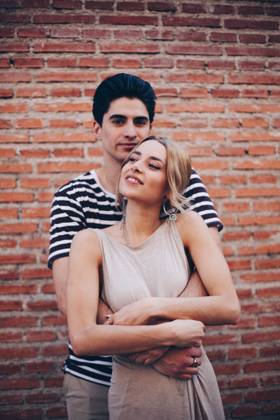 Young cheerful couple in casual clothes having fun during dating outdoors embracing in front of brick wall, Model released Copyright: xRamonxLopezx MR