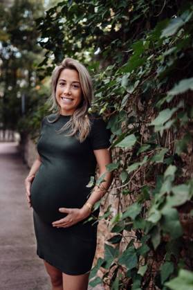 Happy pregnant woman in casual dress stroking belly while standing on pathway in park with green trees in sunny summer day with blue sky, Model released Copyright: xSantixMiquelx MR