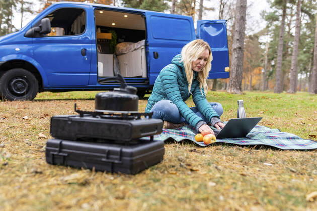 Smiling woman working on laptop while camping in forest at Cannock Chase model released Symbolfoto  WPEF03785