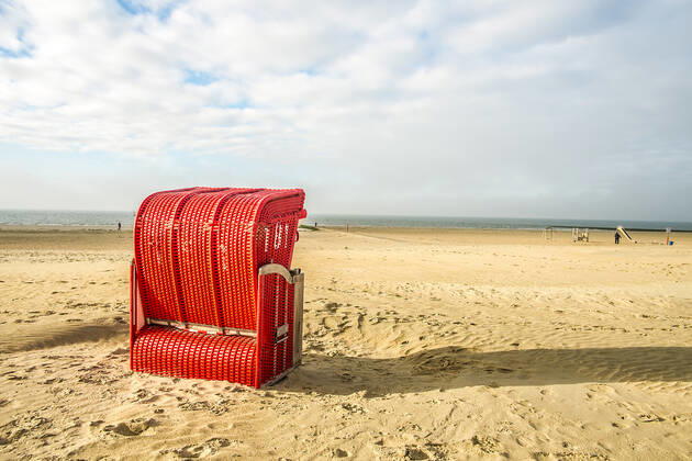 Ein roter Strandkorb steht am Strand von Borkum, Niedersachsen, Deutschland Herbst auf Borkum