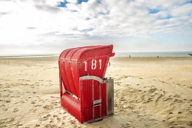 Ein roter Strandkorb steht am Strand von Borkum, Niedersachsen, Deutschland Herbst auf Borkum