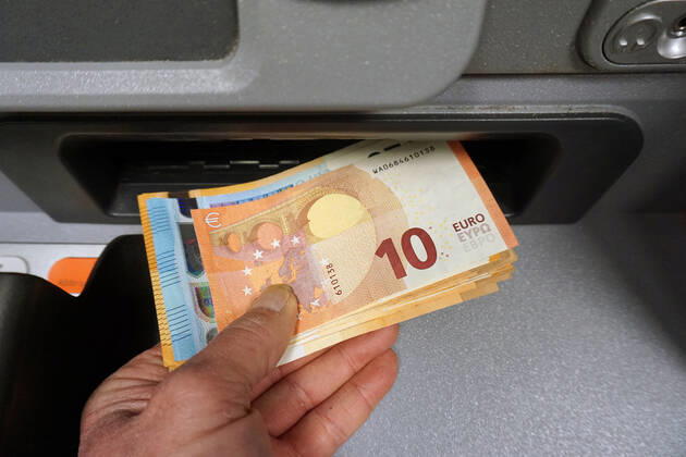 Bargeldversorgung aus einem Automat Eine Person holt an einem Geldautomaten eine größere Menge Bargeld in 50,20 und 10 Euro Geldscheinen ab