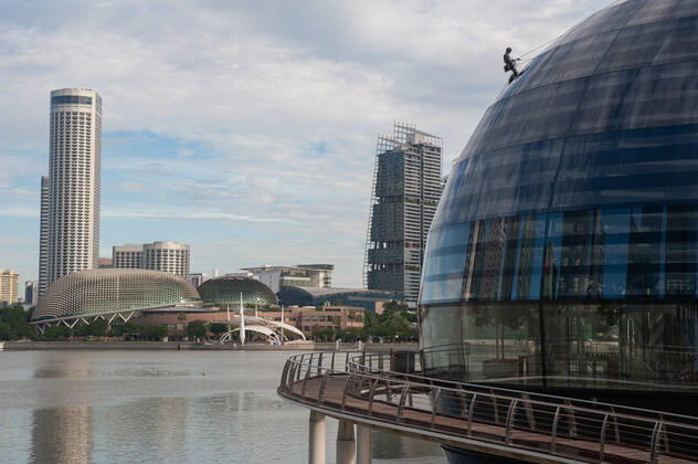 05.01.2021, Singapur, Republik Singapur, Asien - Ein Arbeiter verrichtet Wartungsarbeiten an der kuppelfoermigen Glasfassade des neuen Apple-Vorzeigegeschaefts (Flagshipstore) am Ufer in Marina Bay Sands. Die futuristische Architektur des modernen Einzelhandelsgeschaefts hat die Form einer riesigen Glaskugel, die auf dem Wasser schwebt und ist der dritte Apple Store im suedostasiatischen Stadtstaat. Entworfen wurde das Gebaeude vom englischen Star-Architekten Sir Norman Foster (Foster and Partners). Die schwer vom Handel abhaengige Wirtschaft der Finanzmetropole erlitt im letzten Jahr auf Grund der Corona-Pandemie die schlimmste Rezession in ihrer jungen Geschichte und verzeichnete einen Rueckgang des BIP um 5,8 Prozent.