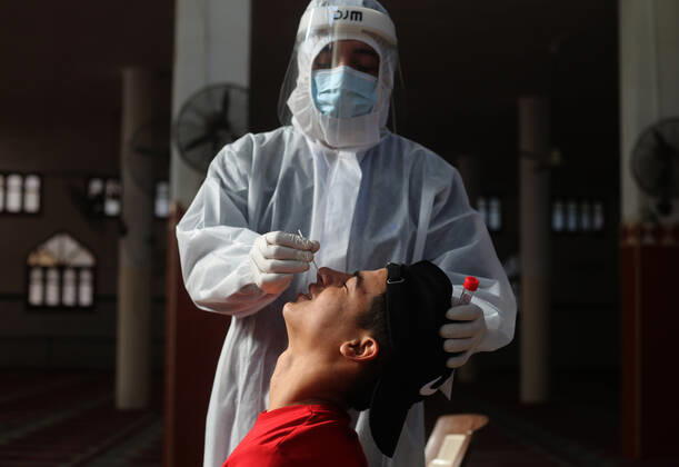 (210111) -- RAFAH, Jan. 11, 2021 -- A medical worker collects a swab sample from a young man to test for the COVID-19 in the southern Gaza Strip city of Rafah, Jan. 11, 2021. (Photo by Xinhua) MIDEAST-GAZA-RAFAH-COVID-19-TEST KhaledxOmar 