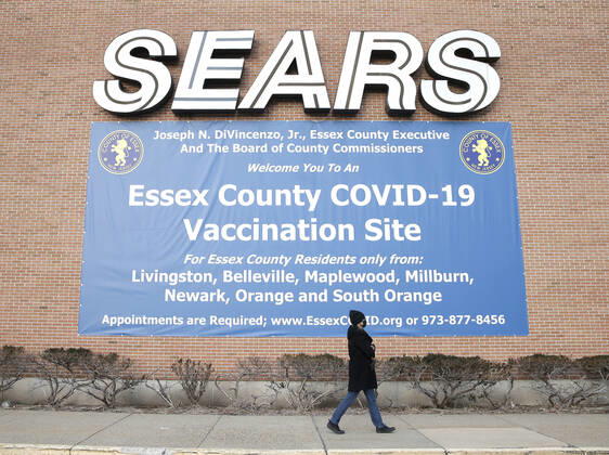 An Essex County COVID-19 Vaccination Site sign hangs below a sign for Sears at a closed Sears retail store location at the Livingston Mall in Livingston, New Jersey on Monday, January 11, 2021. Public health agencies and health-care groups are using the retailer s empty stores to deliver Vaccines in several locations around parts of the United States.  NYP20210111101 JohnxAngelillo