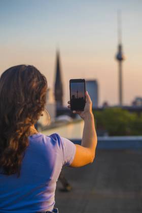 IMAGO Kreativ: Urbane Kultur - Sommer auf den Dächern Woman photographing through smart phone while standing on rooftop model released Symbolfoto NGF00712