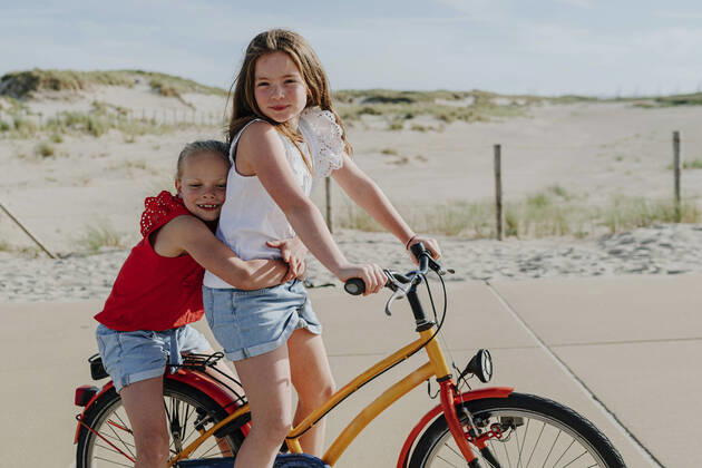 IMAGO Creative: Schwesternschaft Younger sister embracing girl while sitting on bicycle during sunny day model released Symbolfoto OGF00609