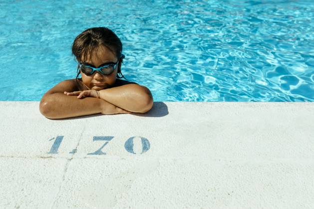 Creative Highlights Symbolbilder Cute boy with arms crossed leaning at poolside on sunny day model released Symbolfoto VABF03614