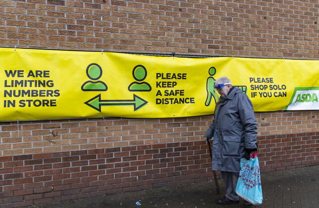 January 11, 2021, Newport, Wales, United Kingdom: A man wearing a face mask walks past a Covid19 awareness sign outside ASDA supermarket in Wales. Newport United Kingdom - ZUMAs197 20210111_zab_s197_018 Copyright: xMayxJamesx