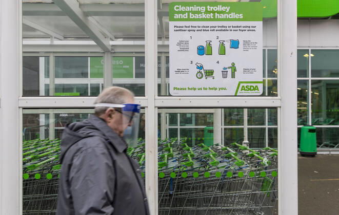January 11, 2021, Newport, Wales, United Kingdom: A man wearing a face mask walks pass Covid19 sign outside ASDA supermarket in Wales. Newport United Kingdom - ZUMAs197 20210111_zab_s197_019 Copyright: xMayxJamesx