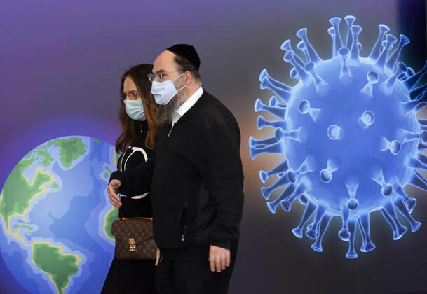 A couple walks past a graphic of the coronavirus in an Israeli vaccination center in Jerusalem, on Tuesday, January 12, 2021. Israel will expand the vaccination drive inoculating teachers and people over 50 years on Wednesday.  JER2021011205 DEBBIExHILL