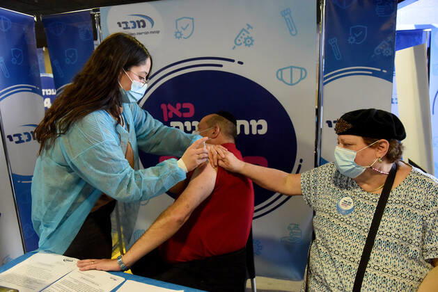 A man receives his second shot of the Pfizer- BioNTech COVID-19 vaccine in an Israeli vaccination center in Jerusalem, on Tuesday, January 12, 2021. Israel will expand the vaccination drive inoculating teachers and people over 50 years on Wednesday.  JER2021011209 DEBBIExHILL