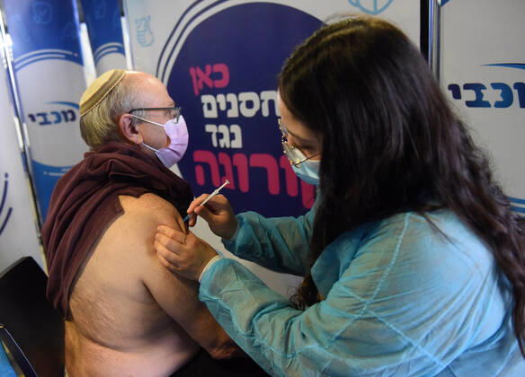 A man receives his second shot of the Pfizer- BioNTech COVID-19 vaccine in an Israeli vaccination center in Jerusalem, on Tuesday, January 12, 2021. Israel will expand the vaccination drive inoculating teachers and people over 50 years on Wednesday.  JER2021011212 DEBBIExHILL