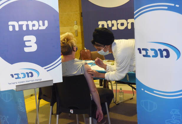 A woman receives her second shot of the Pfizer- BioNTech COVID-19 vaccine in an Israeli vaccination center in Jerusalem, on Tuesday, January 12, 2021. Israel will expand the vaccination drive inoculating teachers and people over 50 years on Wednesday.  JER2021011213 DEBBIExHILL