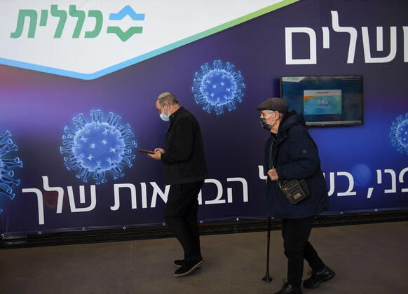 Men walk in an Israeli vaccination center in Jerusalem, on Tuesday, January 12, 2021. Israel will expand the vaccination drive inoculating teachers and people over 50 years on Wednesday.  JER2021011215 DEBBIExHILL