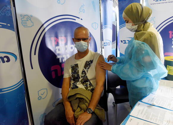 A man receives his second shot of the Pfizer- BioNTech COVID-19 vaccine in an Israeli vaccination center in Jerusalem, on Tuesday, January 12, 2021. Israel will expand the vaccination drive inoculating teachers and people over 50 years on Wednesday.  JER2021011217 DEBBIExHILL