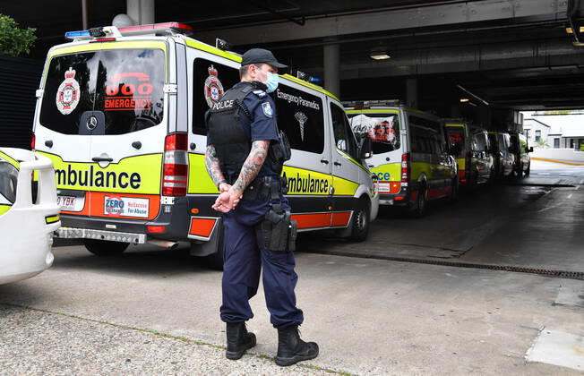QLD CORONAVIRUS COVID19, Ambulances are seen lined up to enter the Hotel Grand Chancellor as a Policeman stands guard in Brisbane, Wednesday, January 13, 2021. The Queensland government is shutting the Hotel Grand Chancellor which is currently operating as a quarantine hotel after six people staying there contracted the deadly UK strain of coronavirus. ( NO ARCHIVING, EDITORIAL USE ONLY, NO USE IN BOOKS WITHOUT CONSENT BRISBANE QLD AUSTRALIA  Copyright: xDARRENxENGLANDx 20210113001513342519