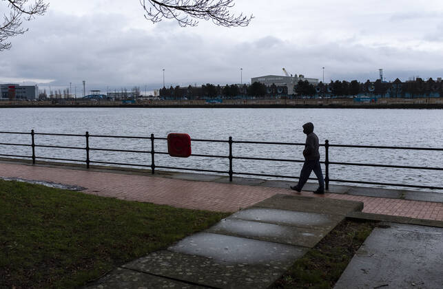 January 12, 2021, Cardiff, Wales, United Kingdom: A man wearing a face mask walks along the Britannia Quay at Cardiff Bay in Wales..1,332 new cases of the coronavirus have been recorded today bringing the total to 172,879 since the pandemic began. The overall death total now stands at 3,997 in Wales. The infection rate is now 403.5 cases per 100,000 people based on the seven days up to January 7. That is down on the 415 previously reported. Cardiff United Kingdom - ZUMAs197 20210112_zab_s197_012 Copyright: xMayxJamesx