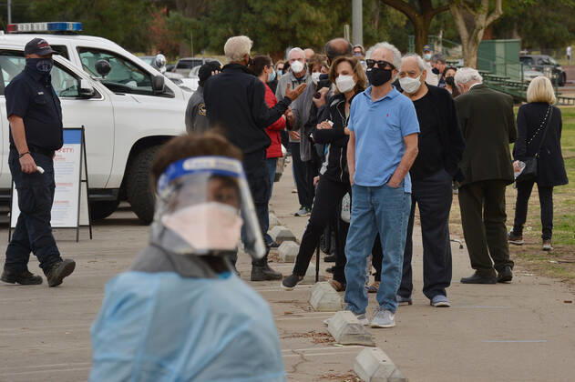 Residents wait in line to be inoculated with the Moderna COVID-19 vaccine at the Balboa Sports Center vaccination site in Los Angeles on Tuesday, January 12, 2021. People aged 65 and older and those with serious underlying health conditions in Los Angeles and across California could quickly become eligible for a COVID-19 vaccine, with federal officials urging states Tuesday to more widely distribute the shots.  LAP2021011202 JIMxRUYMEN