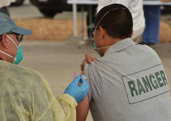 A park ranger is inoculated with the Moderna COVID-19 vaccine at the Balboa Sports Center vaccination site in Los Angeles on Tuesday, January 12, 2021. People aged 65 and older and those with serious.underlying health conditions in Los Angeles and across California could quickly become eligible for a COVID-19 vaccine, with federal officials urging states Tuesday to more widely distribute the shots.  LAP2021011203 JIMxRUYMEN