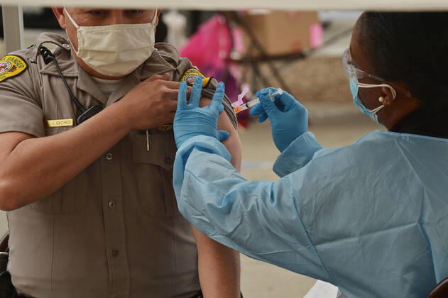 A park ranger is inoculated with the Moderna COVID-19 vaccine at the Balboa Sports Center vaccination site in Los Angeles on Tuesday, January 12, 2021. People aged 65 and older and those with serious.underlying health conditions in Los Angeles and across California could quickly become eligible for a COVID-19 vaccine, with federal officials urging states Tuesday to more widely distribute the shots.  LAP2021011204 JIMxRUYMEN