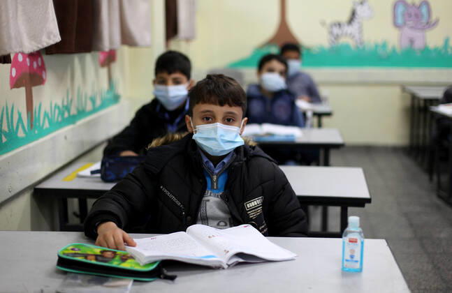 January 13, 2021, Gaza City, Gaza Strip, Palestinian Territory: Palestinian students wear protective face masks, listen to their teacher as schools gradually reopen amid the coronavirus disease (COVID-19) outbreak, at their school in Gaza city, on January 13, 2021. In a written statement, the Palestinian Health Ministry said 7 more people have died from the virus in the last 24 hours in Gaza strip and that 437 new cases have been identified Gaza City Palestinian Territory - ZUMAap3_ 20210113_zaf_ap3_041 Copyright: xMahmoudxAjjourx