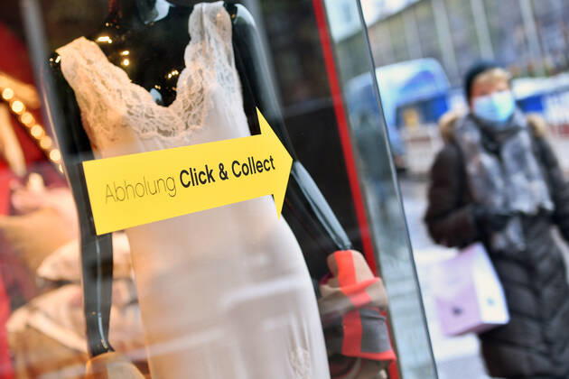 Themenbild:Abholung Click and Collect in Muenchen am 12.01.2021. An einem Schaufenster eines Bekleidungsgeschaeftes klebt ein Richtungspfeil mit dem Hinweis zur Abholung online bestellter Waren im Geschaeft.
