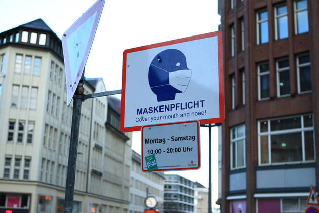 Ein an einem Laternenpfahl befestigtes Schild weist darauf hin, dass in der Mönckebergstraße in Hamburg zu bestimmten Zeiten Maskenpflicht herrscht. Altstadt Hamburg