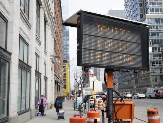Pedestrians walk by a sign that says Javits Covid Vaccine one block from the Jacob K. Javits Convention Center,in New York City on Wednesday, January 13, 2021. The Javits Convention Center which served as a massive field hospital last spring when New York City was the epicenter of the pandemic, now will serve as a huge vaccine distribution center.  NYP20210113199 JohnxAngelillo