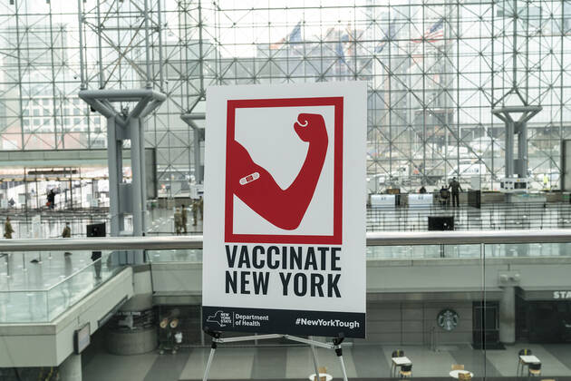 NY: Opening of mass vaccination site at Jacob Javits Center Poster promoting importance of vaccination seen inside of Jacob Javits Center on opening vaccination site. Health care personnel, medical examiners, funeral workers, coroners, essential workers, police officers, firefighters, people older than 65 and more eligible right now to get vaccination in New York State. New York New York United States Copyright: LevxRadin