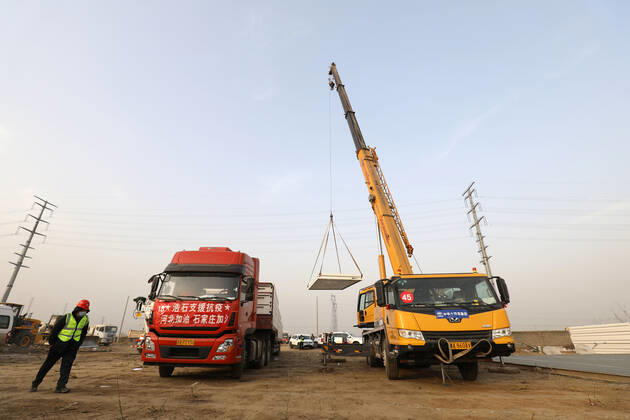 (210114) -- SHIJIAZHUANG, Jan. 14, 2021 -- Workers unload materials at the construction site of a centralized medical observation center in Shijiazhuang, capital of north China s Hebei Province, Jan. 14, 2021. Construction workers on Wednesday started building a centralized medical observation center in Shijiazhuang, where clustered COVID-19 cases occurred. The isolation center will likely cover 33 hectares of area near a village in Zhengding County, Shijiazhuang. Three integrated housing producers in Tangshan City, Hebei, have been entrusted to produce 3,000 makeshift wards for the center. Each ward has a space of 18 square meters. ) CHINA-HEBEI-SHIJIAZHUANG-ISOLATION CENTER-CONSTRUCTION (CN) YangxShiyao