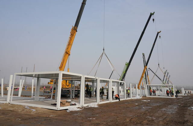 (210114) -- SHIJIAZHUANG, Jan. 14, 2021 -- Workers put up prefabs on the construction site of a centralized medical observation center in Shijiazhuang, capital of north China s Hebei Province, Jan. 14, 2021. Construction workers on Wednesday started building a centralized medical observation center in Shijiazhuang, capital of north China s Hebei Province, where clustered COVID-19 cases occurred. The isolation center will likely cover 33 hectares of area near a village in Zhengding County, Shijiazhuang. Three integrated housing producers in Tangshan City, Hebei, have been entrusted to produce 3,000 makeshift wards for the center. Each ward has a space of 18 square meters. ) CHINA-HEBEI-SHIJIAZHUANG-COVID-19-ISOLATION CENTER-CONSTRUCT
