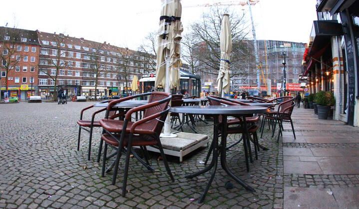 Aufeinander gestapelte Stühle stehen vor einem geschlossenen Restaurant auf dem menschenleeren Winterhuder Marktplatz in Hamburg. Winterhude Hamburg