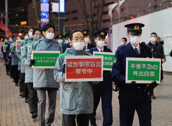 January 15, 2018, Tokyo, Japan - Local government officers and police officers hold placards and ask people to stay home at Shinjuku entertainment district amid outbreak of the new coronavirus in Tokyo on Friday, January 15, 2021. Japanese government declared a state of emergency on Tokyo and 10 other prefectures this week and requested nightclubs and restaurants to close 8 pm.  (152049270)