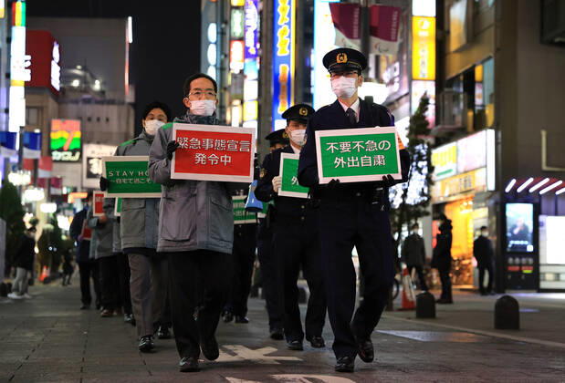 January 15, 2018, Tokyo, Japan - Local government officers and police officers hold placards and ask people to stay home at Shinjuku entertainment district amid outbreak of the new coronavirus in Tokyo on Friday, January 15, 2021. Japanese government declared a state of emergency on Tokyo and 10 other prefectures this week and requested nightclubs and restaurants to close 8 pm.  (152049273)