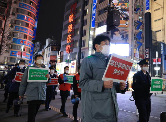 January 15, 2018, Tokyo, Japan - Local government officers and police officers hold placards and ask people to stay home at Shinjuku entertainment district amid outbreak of the new coronavirus in Tokyo on Friday, January 15, 2021. Japanese government declared a state of emergency on Tokyo and 10 other prefectures this week and requested nightclubs and restaurants to close 8 pm.  (152049277)