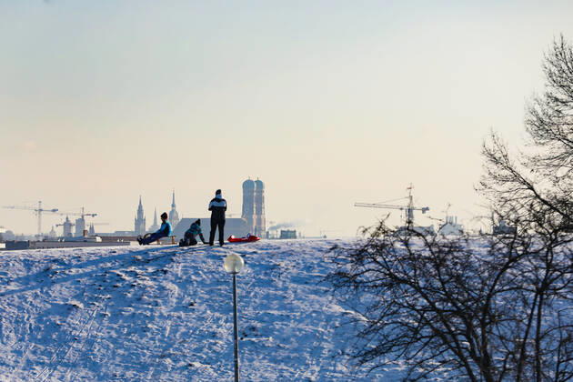 Freizeitaktivitäten im Olympiapark 15.01.2021 MÜNCHEN Schlittenfahrer auf dem Olympiaberg - Im Hintergrund die Skyline von München, inklusive Frauenkirche. München Bayern Deutschland