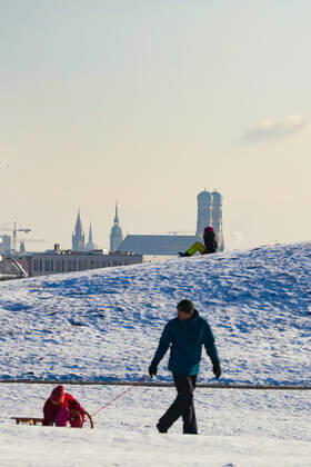 Freizeitaktivitäten im Olympiapark 15.01.2021 MÜNCHEN Schlittenfahrer auf dem Olympiaberg - Im Hintergrund die Skyline von München, inklusive Frauenkirche. München Bayern Deutschland