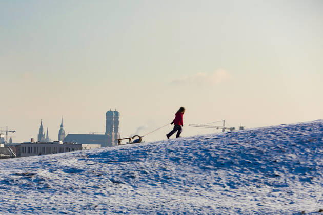 Freizeitaktivitäten im Olympiapark 15.01.2021 MÜNCHEN Schlittenfahrer auf dem Olympiaberg - Im Hintergrund die Skyline von München, inklusive Frauenkirche. München Bayern Deutschland