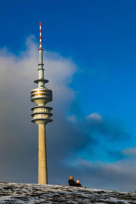Freizeitaktivitäten im Olympiapark 15.01.2021 MÜNCHEN Zwei Personen auf einem Schlitten - der Olympiaturm im Hintergrund. München Bayern Deutschland