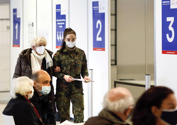 Impfzentrum Schoenefeld Schoenefeld, DEU, 15.01.2021 - Eine Bundeswehrsoldatin bringt im Impfzentrums im Terminal 5 des BER Flughafens eine aeltere Frau zur Impfung. Es ist das dritte Impfzentrum in Brandenburg Geleitet wird das Impfzentrums durch die Johanniter-Unfall-Hilfe. Impfungen werden vor Ort durch medizinisches Personal der Bundeswehr ausgefuehrt. Schoenefeld Brandenburg Deutschland