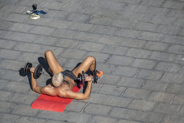 January 17, 2021, Barcelona, Catalonia, Spain: A man wearing shorts and with a bare torso is seen on the ground practicing bodybuilding on Passeig del Mare Nostrum..With public sports centers and gyms closed due to the increase in Covid-19 infections, many individual and social sports activity is taking place in public space such as open areas near the beaches. Barcelona Spain - ZUMAs197 20210117_zaa_s197_069 Copyright: xPacoxFreirex
