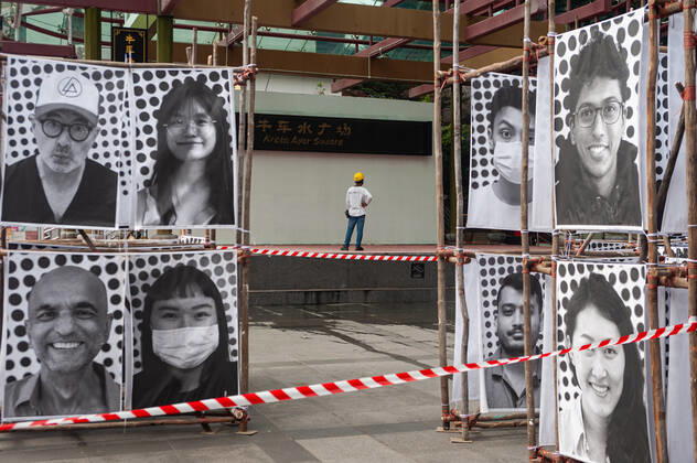05.01.2021, Singapur, Republik Singapur, Asien - Ein Arbeiter steht in Zeiten der anhaltenden Corona-Pandemie (Covid-19) auf einem Podium des Kreta Ayer Square in Chinatown, vor dem Portraits einer oeffentlichen Ausstellung zu sehen sind. Die Portraits des Kuenstlers JR in grossformatigen Abbildungen sind Teil des globalen Projekts INSIDE OUT, in dem jedermann die Moeglichkeit hat mit seinem Portrait teilzunehmen und damit eine Aussage zu machen, wofuer man steht. Dabei handelt es sich um eine globale Plattform fuer Menschen, um ihre ungeschriebenen Geschichten zu teilen und um Botschaften der persoenlichen Identitaet in oeffentliche Kunstwerke umzusetzen.++ Rechte Dritter nicht beim Fotografen, keine Haftung bei Forderungen von abgebildete